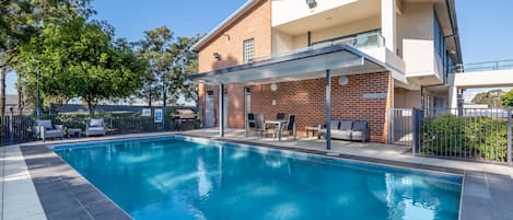 Una piscina al aire libre, sillones reclinables de piscina