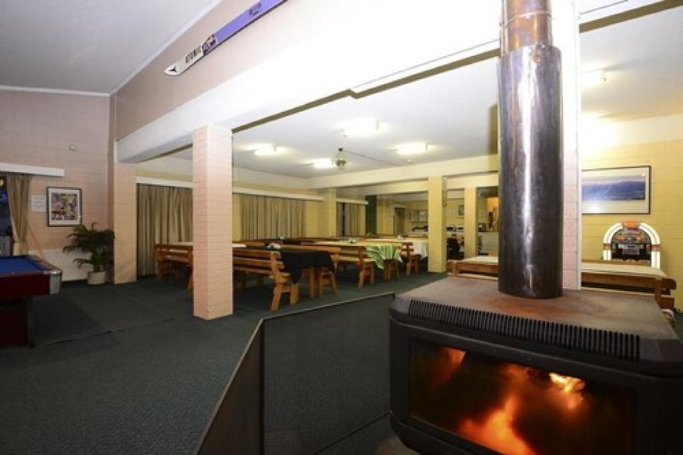 A room with a wood-burning stove, a pool table, and a dining area with tables and chairs.