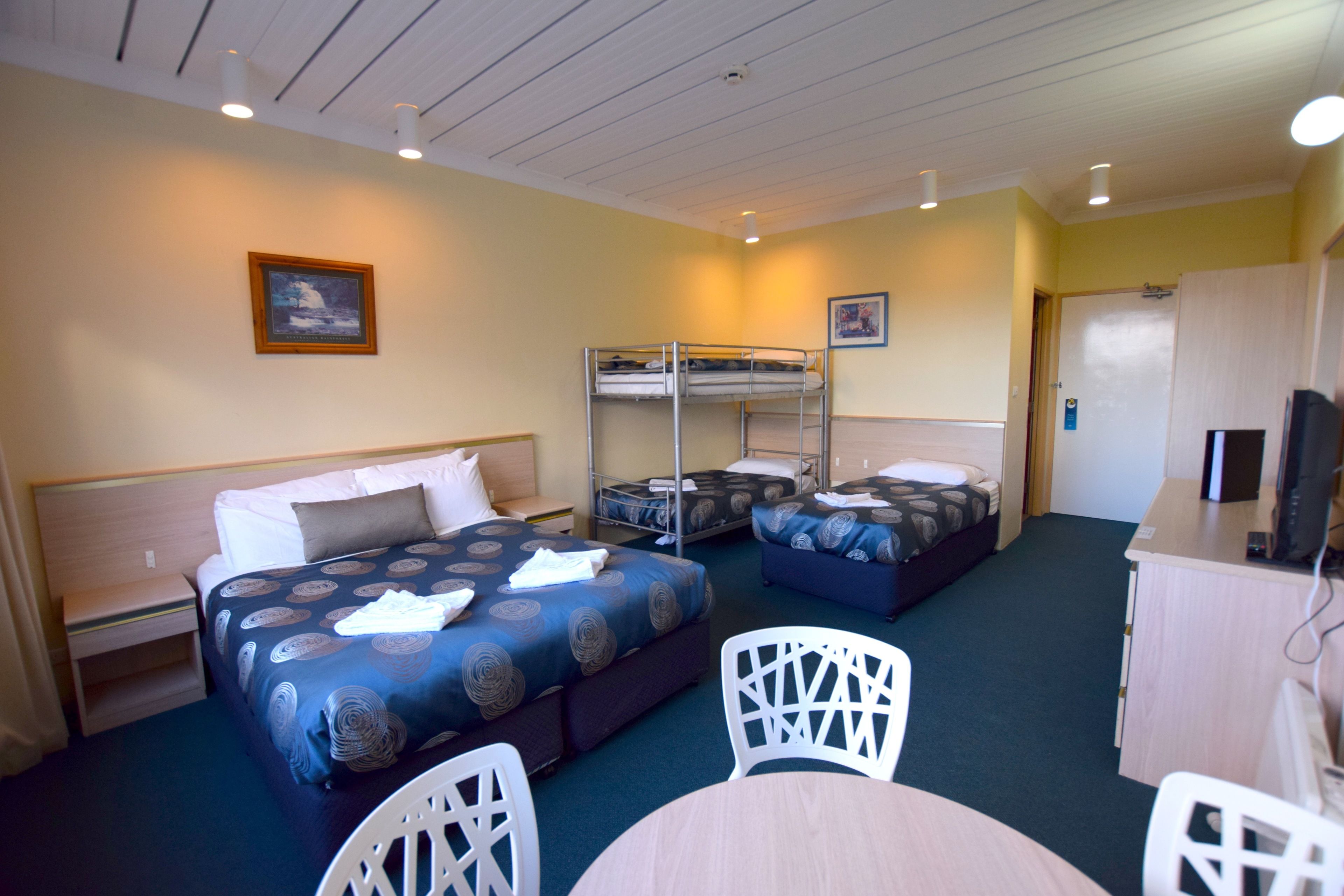 A hotel room with bunk beds, a desk, and a chair.