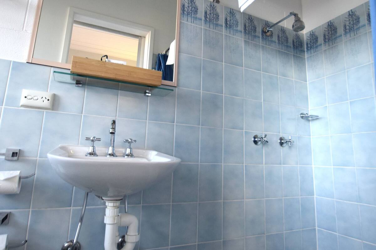 Un bagno con lavandino, specchio e doccia.
