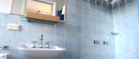A bathroom with a sink, mirror, and shower.
