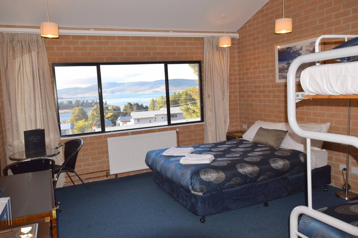 Camera da letto con un letto a castello, una scrivania e vista su un lago e sulle montagne.