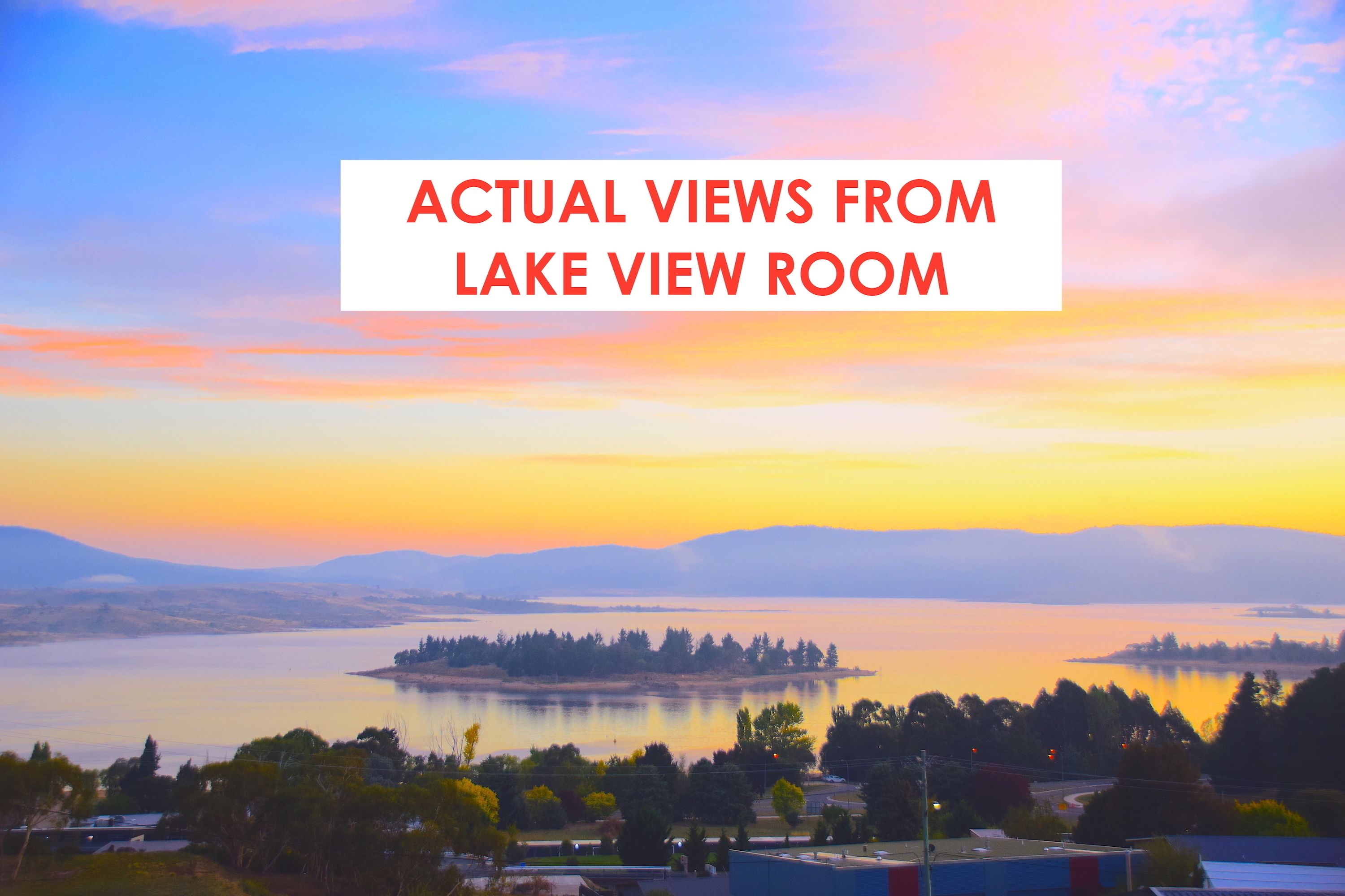 A lake view room with a scenic sunset view, a calm lake, and distant hills.