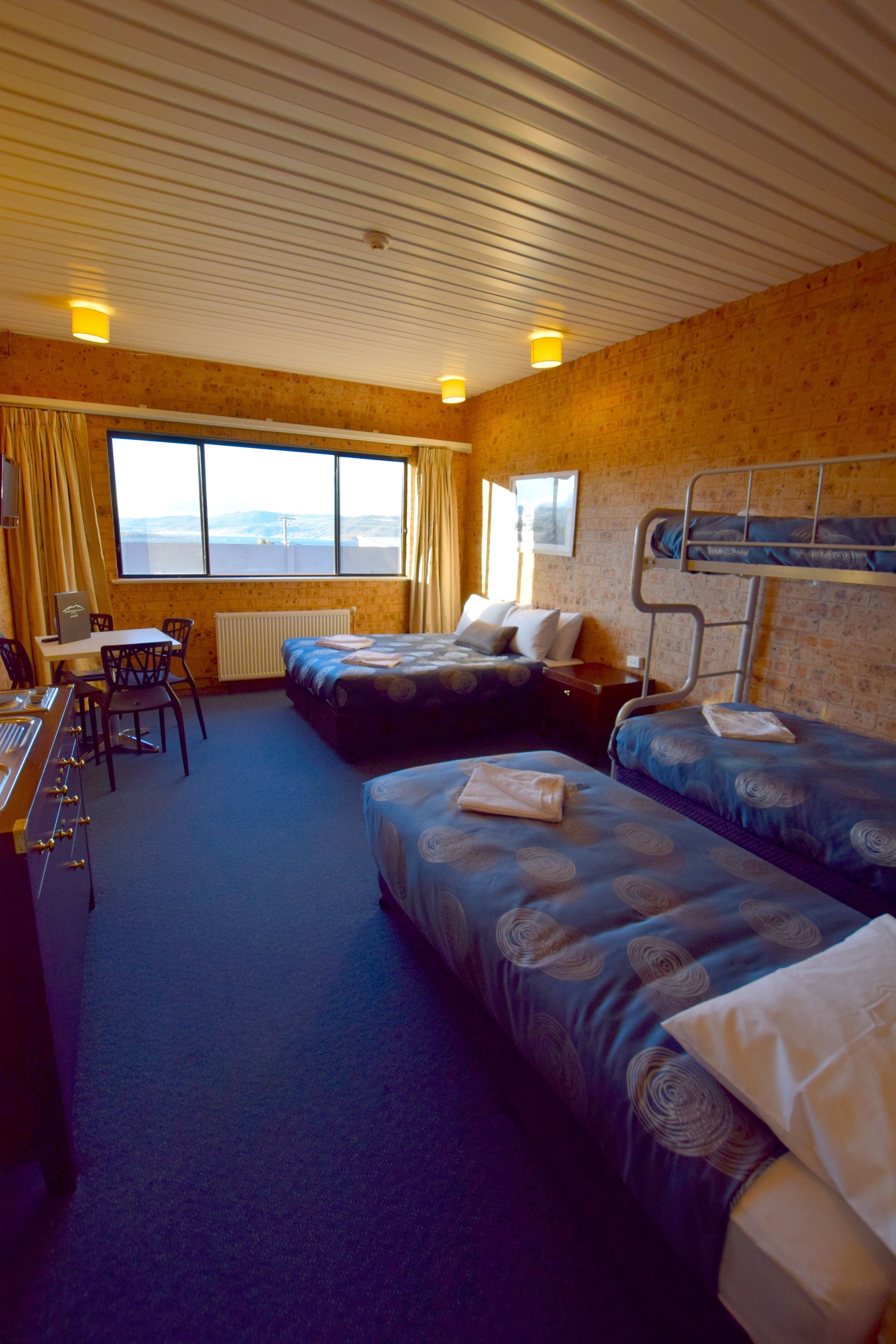 A hotel room with two beds, a desk with a computer, a chair, and a view of the outdoors.
