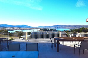 Une terrasse avec des sièges extérieurs et une vue sur un lac et des montagnes.