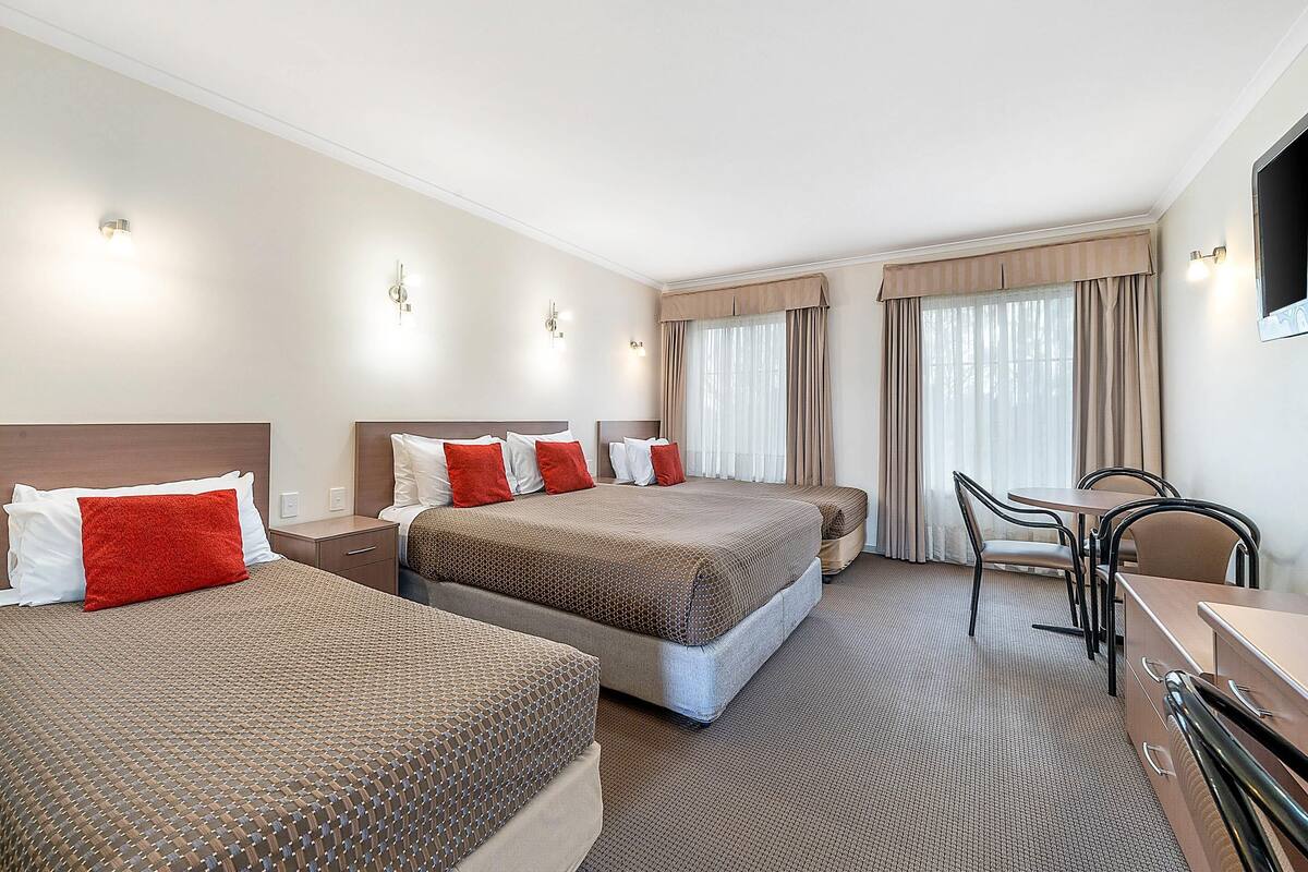 Una habitación de hotel con dos camas, un escritorio, sillas y un televisor.