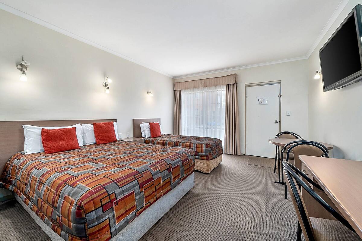 Habitación de hotel con dos camas, televisión, escritorio y una silla.