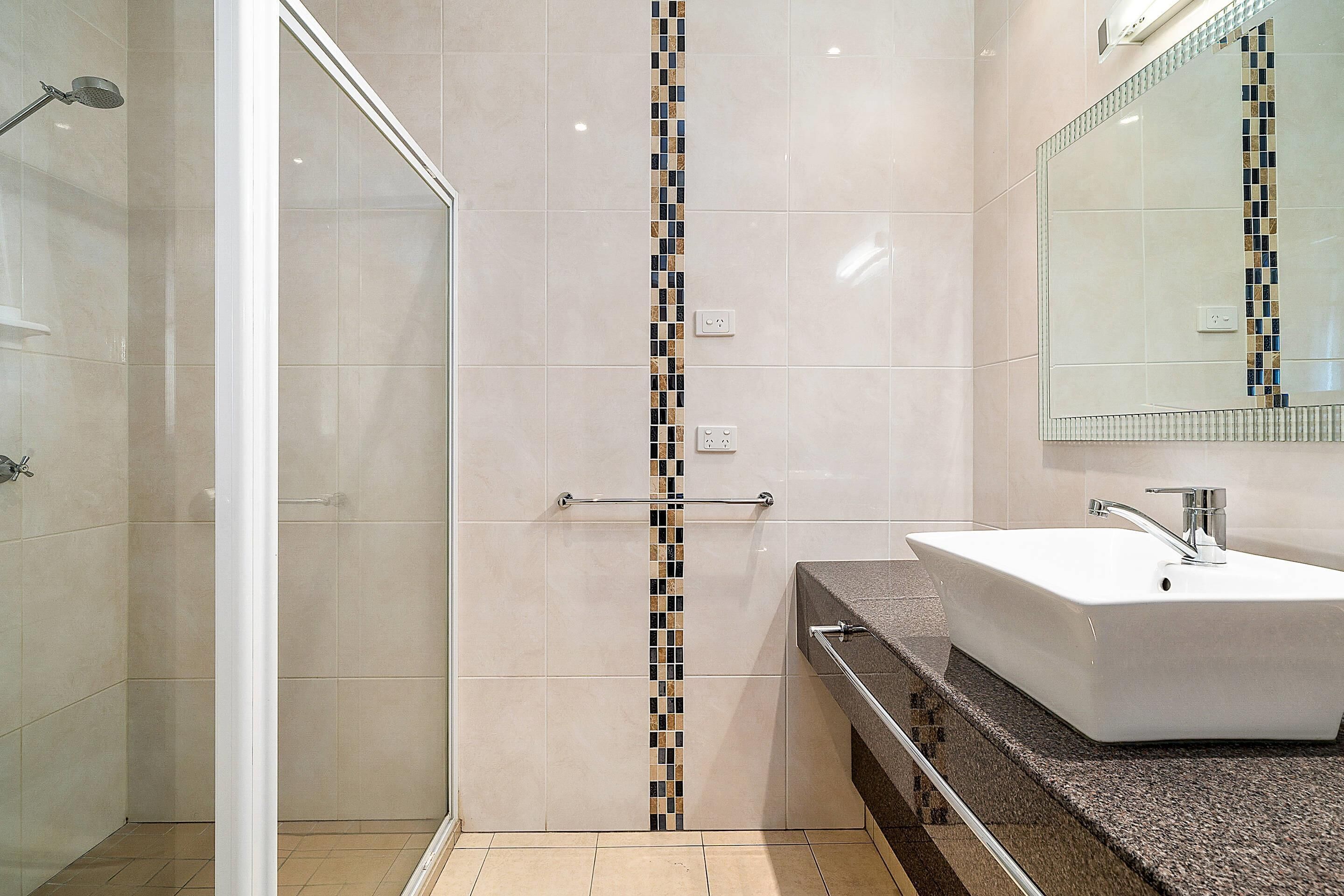 A bathroom with a shower, a sink, and a mirror.