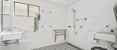 A bathroom with a toilet, bidet, sink, and shower.