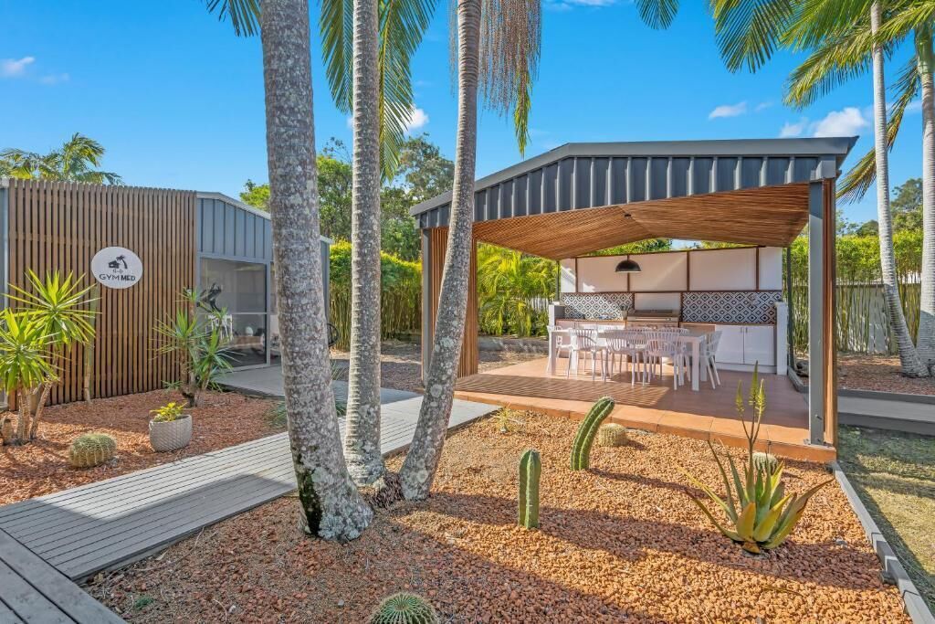 Un espace extérieur moderne, aménagé en terrasse, avec une pergola en bois, une table à manger et des chaises.