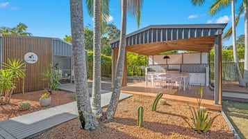 Un espace extérieur moderne, aménagé en terrasse, avec une pergola en bois, une table à manger et des chaises.