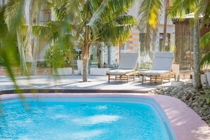 A swimming pool with lounge chairs and palm trees. - The Med Motel (Crescent Head)