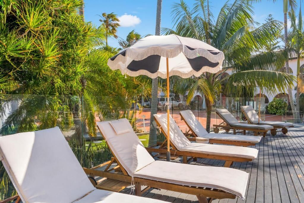 Ein Poolbereich mit Liegestühlen und einem großen Sonnenschirm.