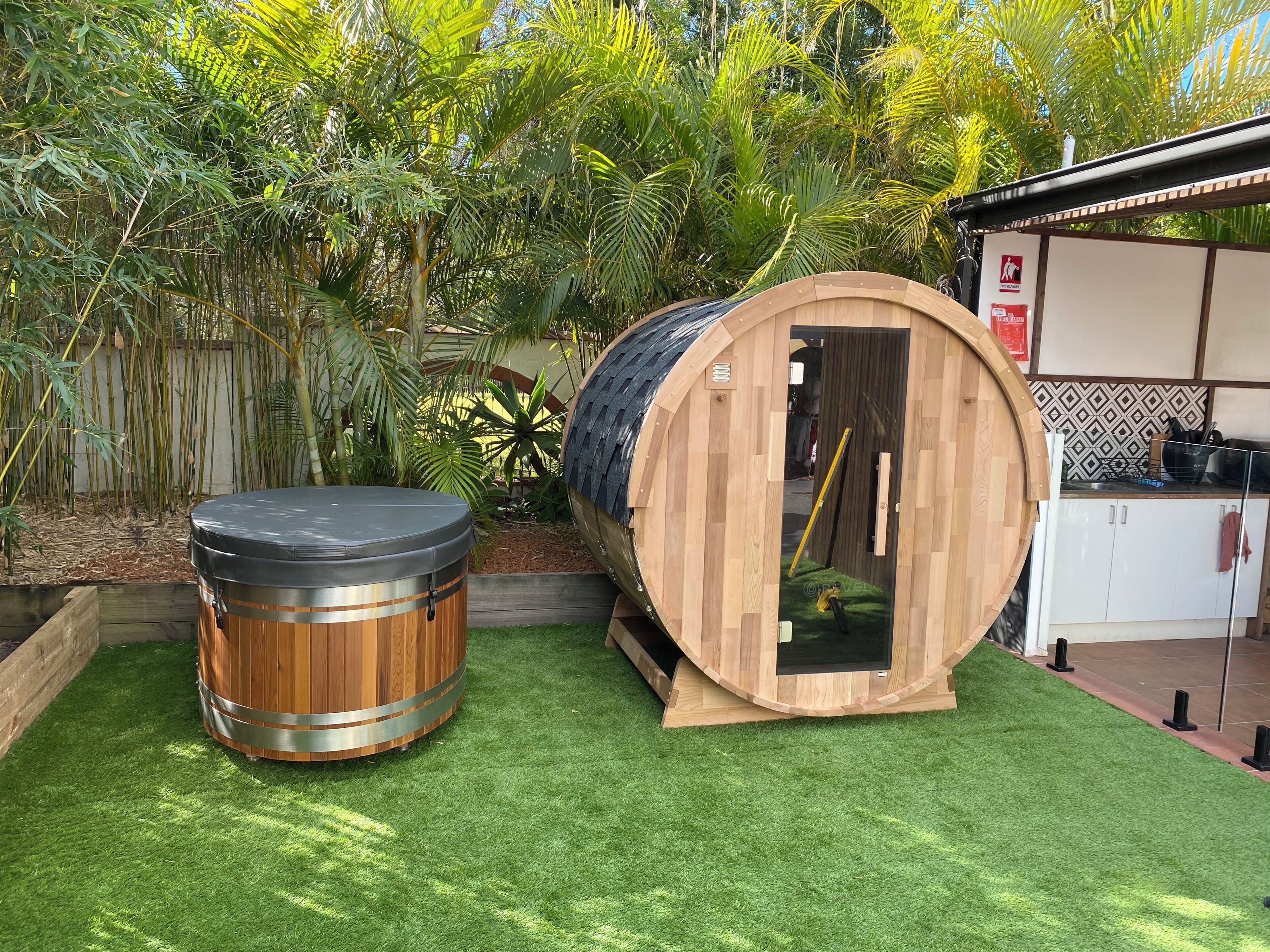 A wooden barrel-shaped structure with a door, a cylindrical drum, and a kitchen area with cabinets and a tiled backsplash.