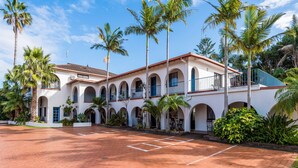 A building with a courtyard, palm trees, and a red brick floor.