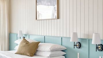 A hotel room with a bed, a nightstand, a lamp, and a framed picture on the wall.
