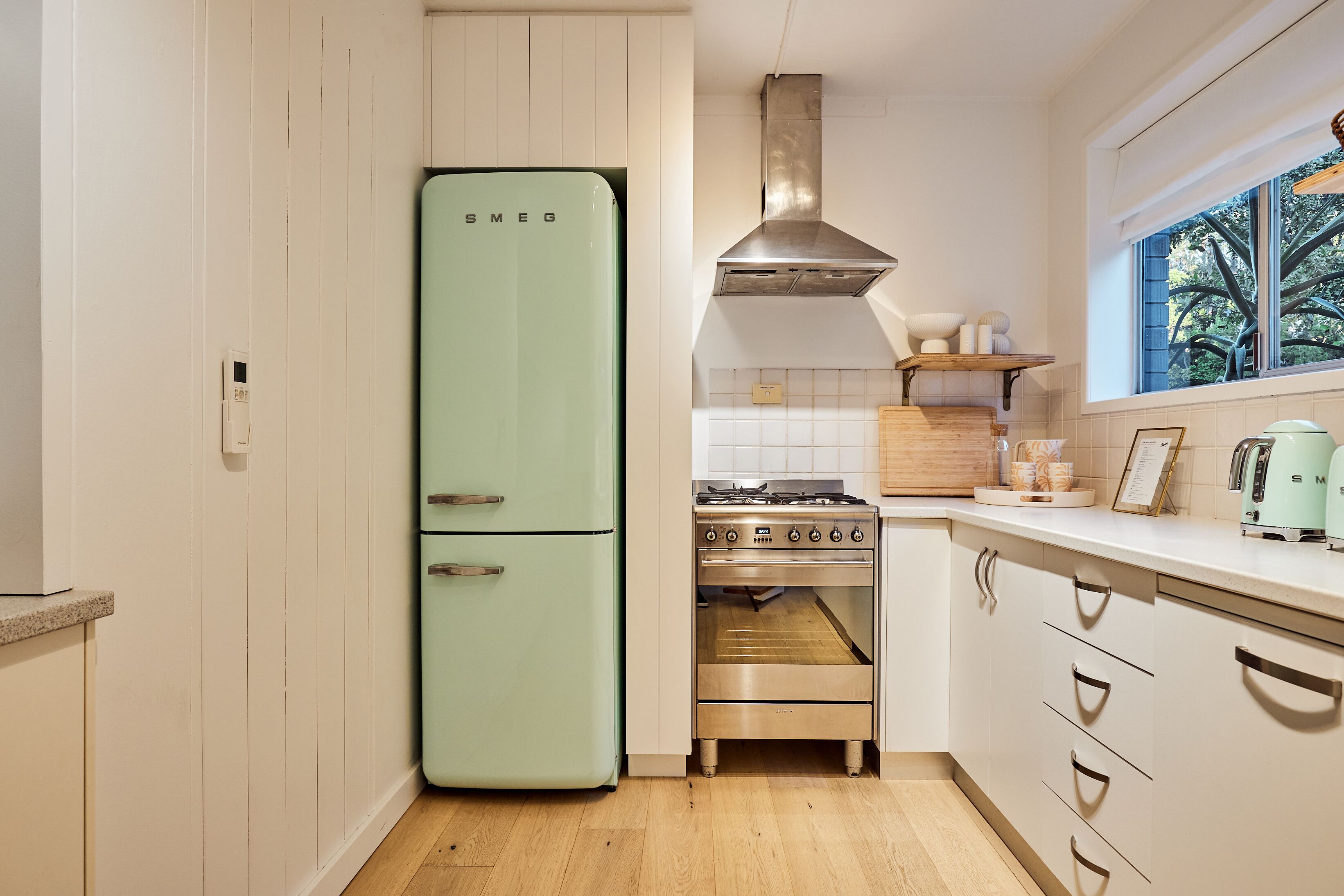 Una cocina con un refrigerador de estilo vintage, una estufa a gas y armarios de madera.