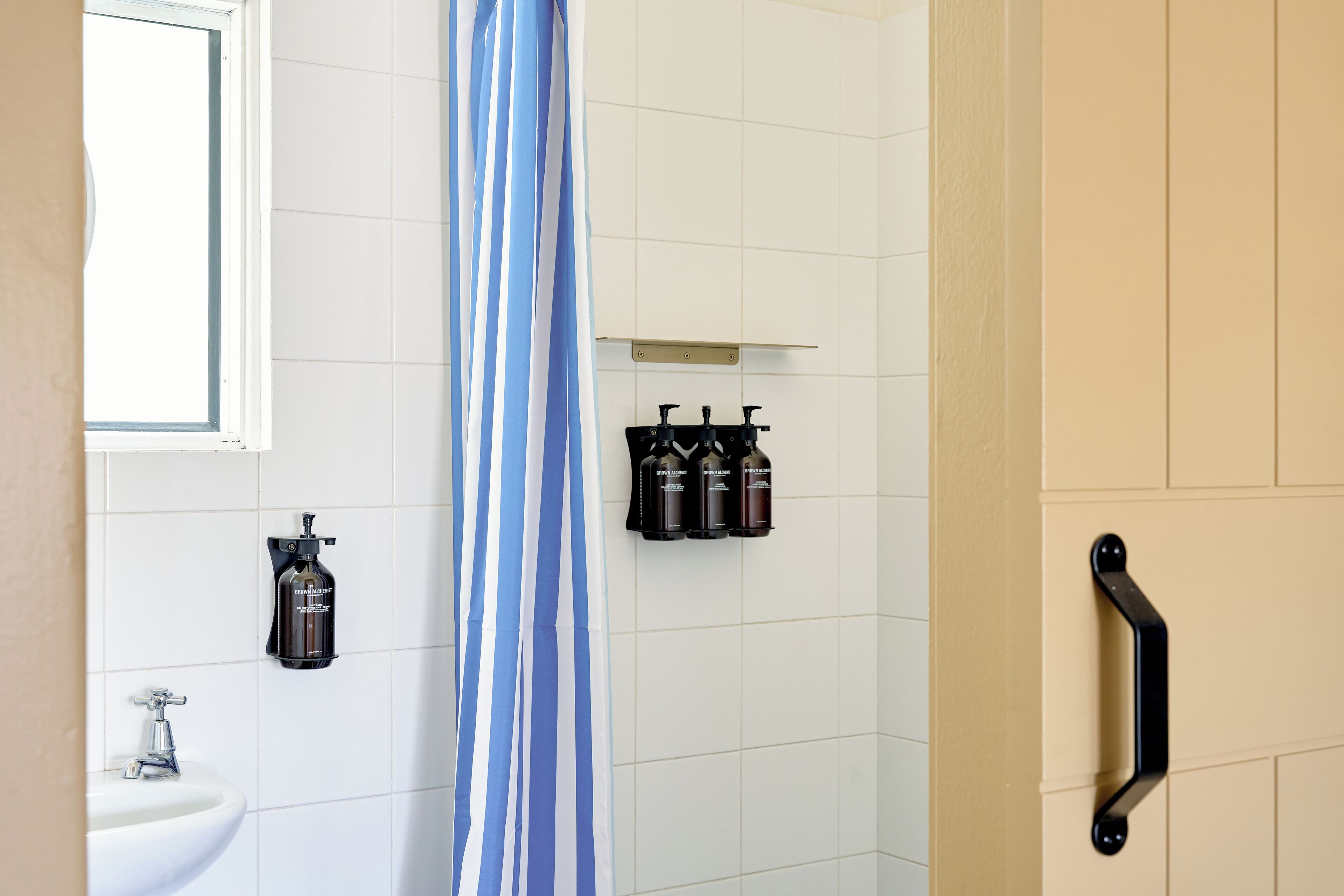 A bathroom with a white sink, a shower curtain, and a black towel rack.