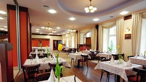 A restaurant with multiple tables, each set with white tablecloths and silverware. - Hotel Carskie Koszary (Zamosc)