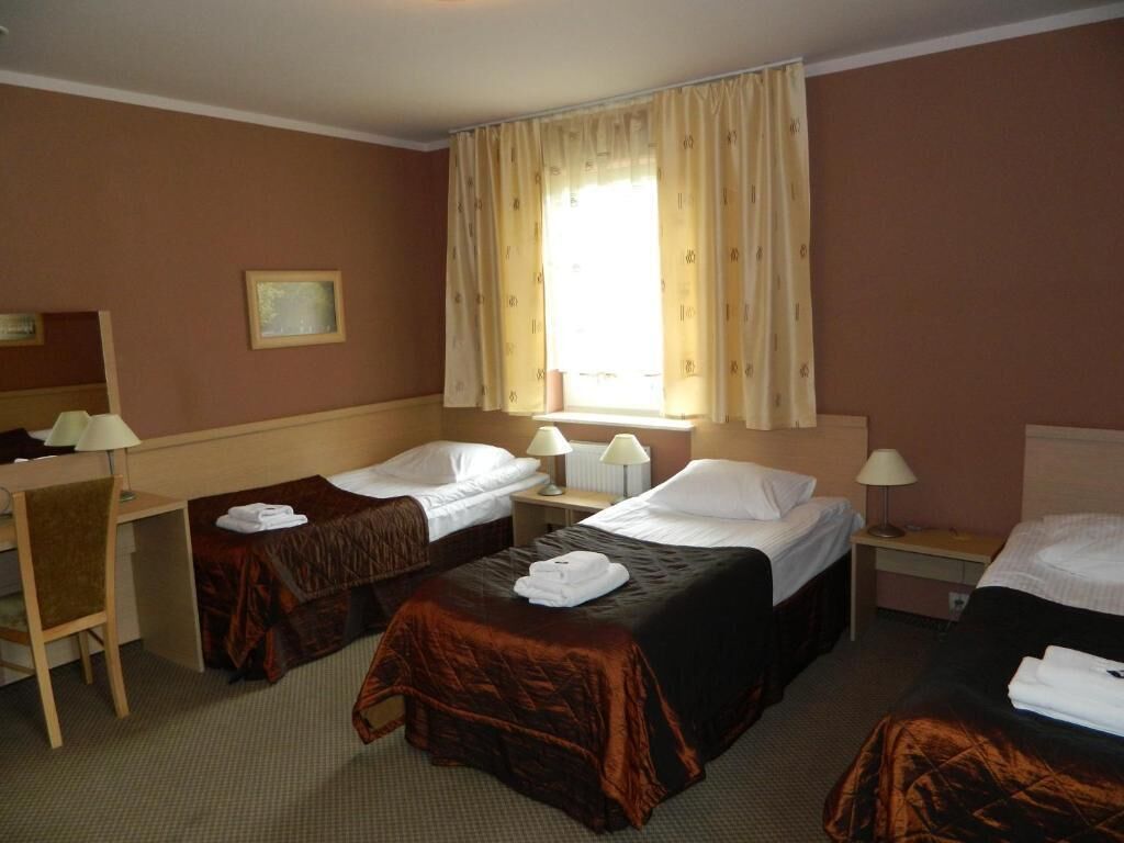 A hotel room with two single beds, a desk, and a chair.