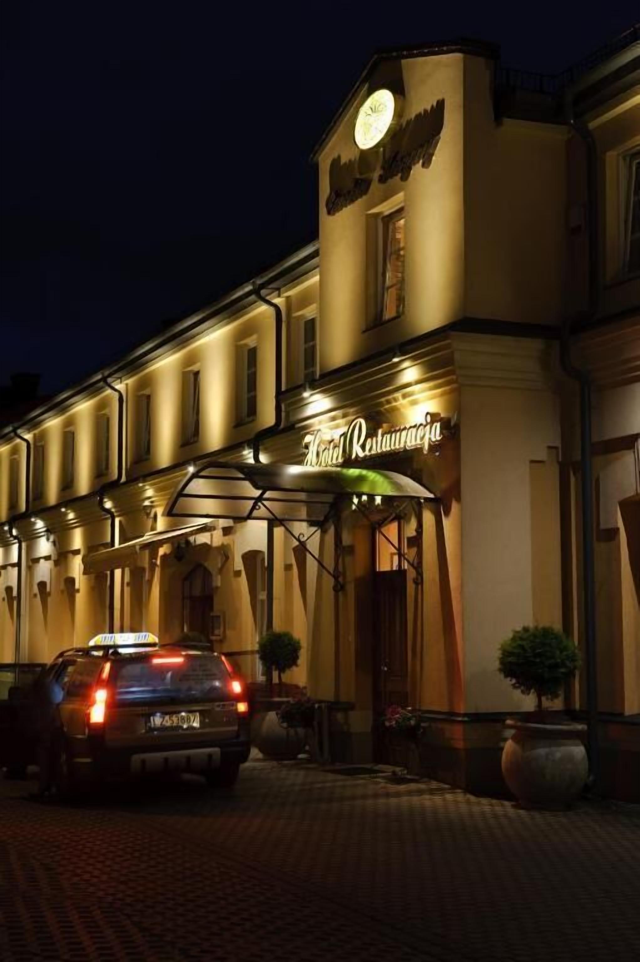 A hotel entrance with a sign reading "Hotel Restauranteja" and a car parked in front.