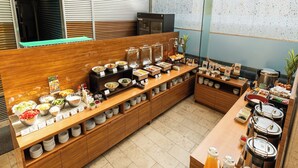Un buffet proposant une variété de plats et de boissons, avec des comptoirs en bois et un espace cuisine en arrière-plan.