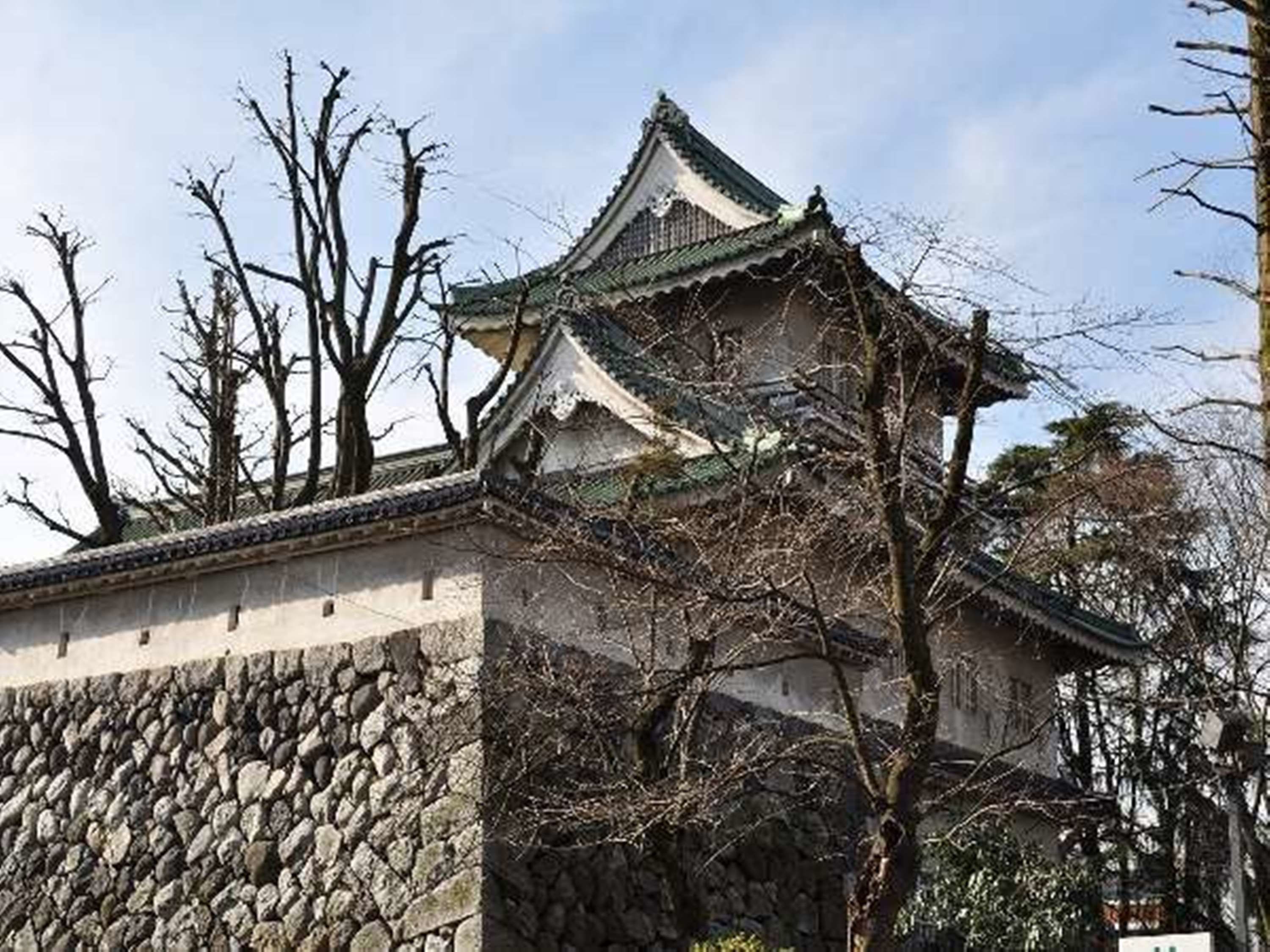 A traditional Japanese castle with a stone wall and tiled roof.
