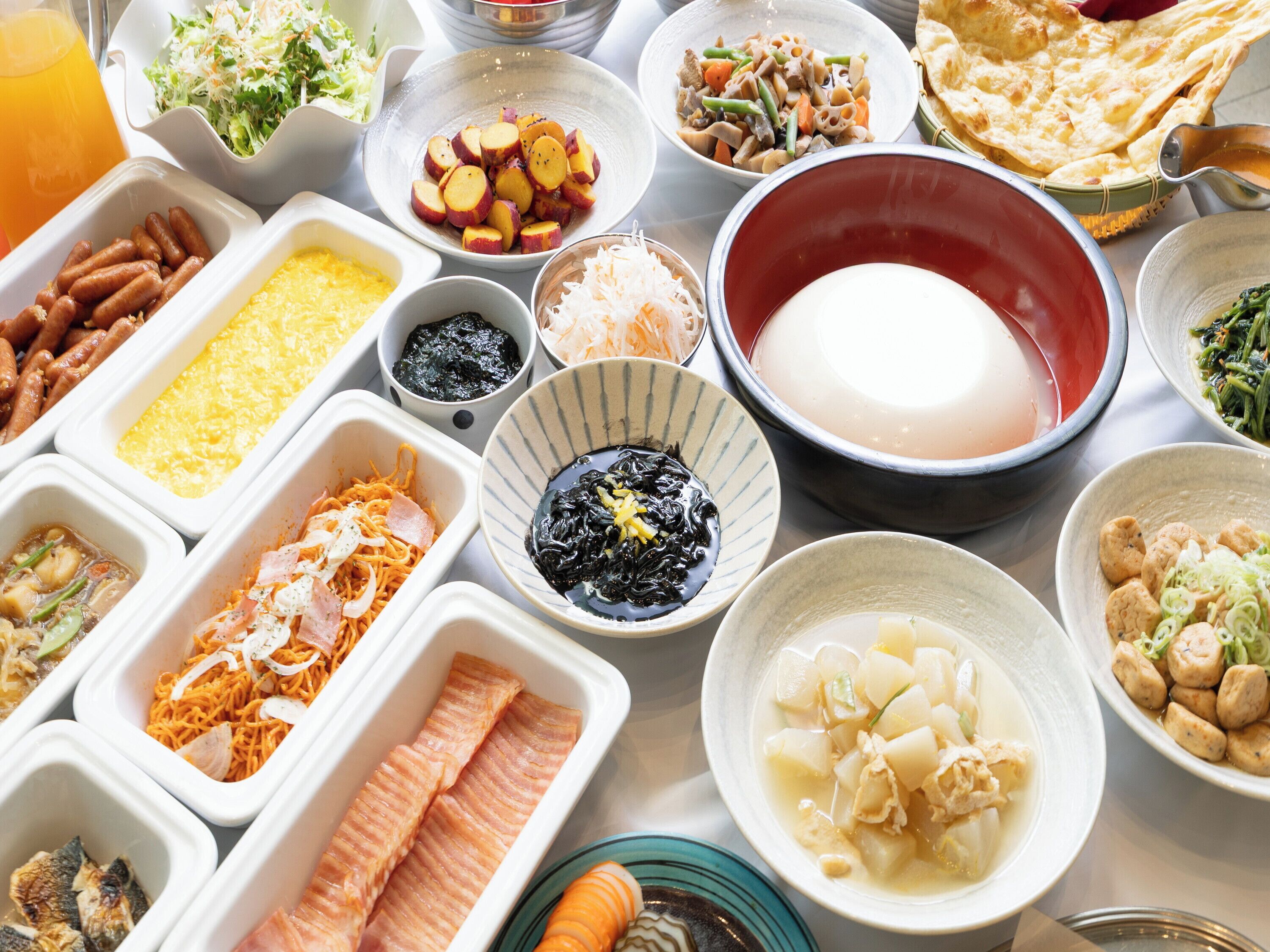 A variety of dishes and food items on a table, including bowls of soup, plates of vegetables, and other prepared foods.