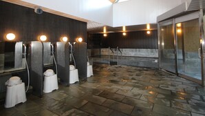 Un spa moderne avec des sols carrelés en pierre, un plafond en bois et plusieurs fauteuils de massage dotés d’un éclairage intégré.