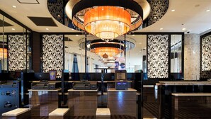 Un hall d’hôtel doté d’un grand lustre, de comptoirs d’enregistrement et de murs aux motifs décoratifs.