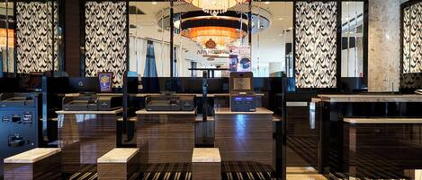 A hotel lobby with a large chandelier, check-in counters, and patterned walls.