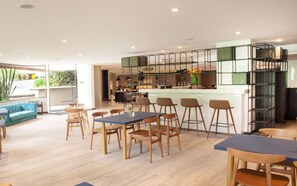 A modern kitchen with a bar area, wooden flooring, and a view of the outdoors. - Viaggio Urbano (Bogotá)