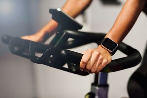 A close-up of a person's hands on a stationary bike handlebar with a smartwatch. - Viaggio Urbano (Bogotá)