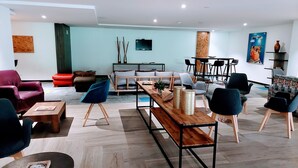 A modern lounge area with seating arrangements, a wooden coffee table, and a television mounted on the wall. - Viaggio Urbano (Bogotá)
