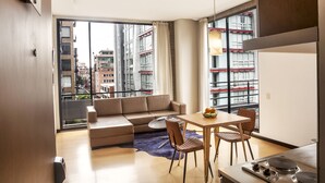 Apartamento moderno com sala de estar, espaço para refeições e grandes janelas com vista para a cidade.