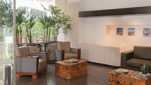 Um lobby moderno com área de estar, mesa de centro de madeira e plantas em vasos.