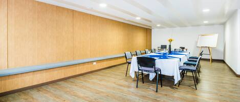 A conference room with a long table, chairs, a whiteboard, and a projector.