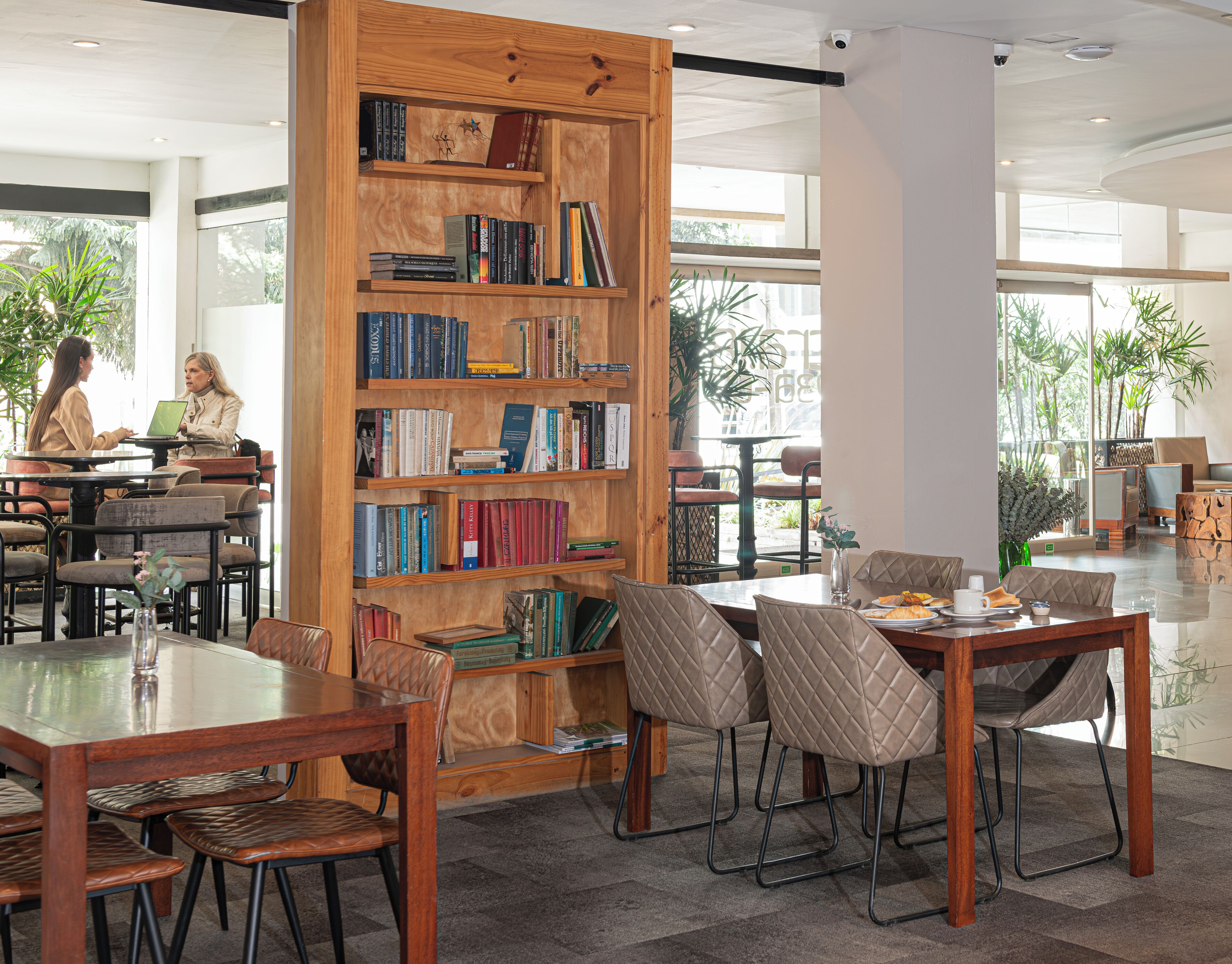 A modern library with bookshelves, a coffee table, and leather chairs.