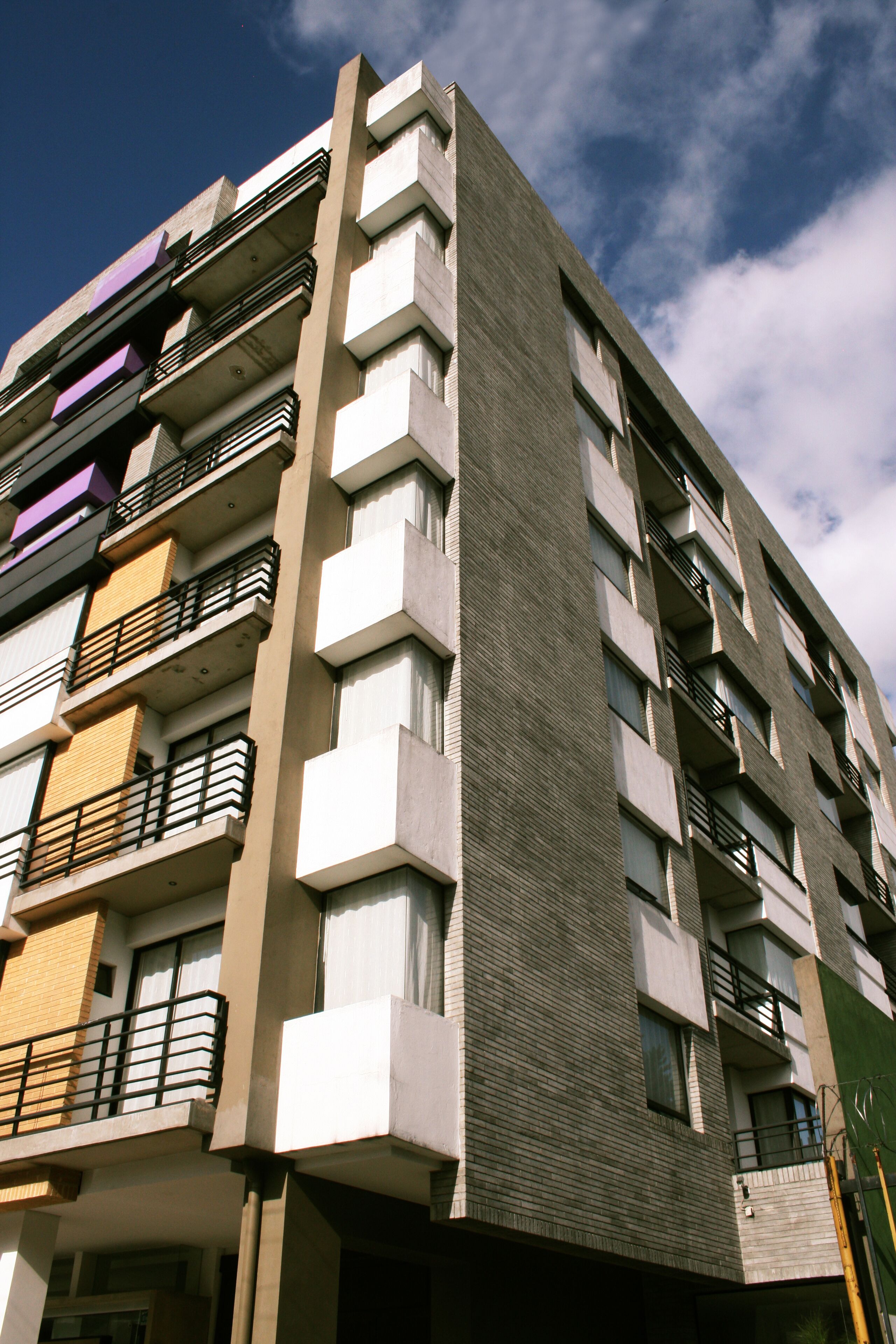 En bygning med flere etager, moderne arkitektur, med altaner og store vinduer.
