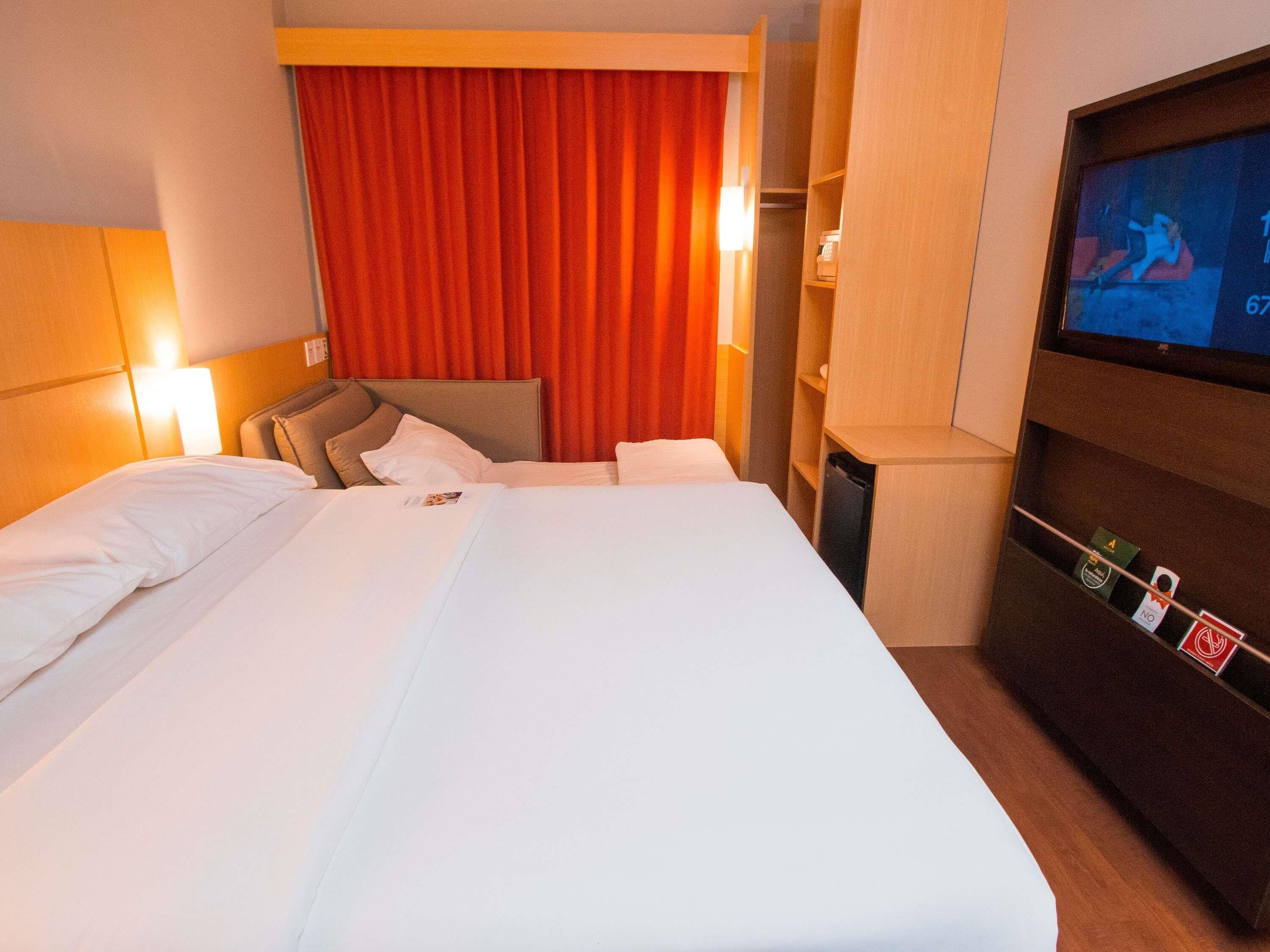 Een hotelkamer met een groot bed, een televisie en een minibar.
