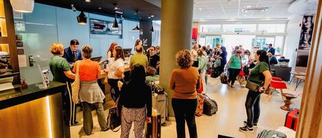 A busy airport check-in area with a counter, seating, and a large pillar.