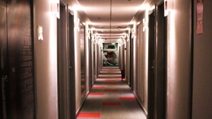 Un long couloir étroit, typique des hôtels, avec des portes des deux côtés et un sol recouvert de moquette.