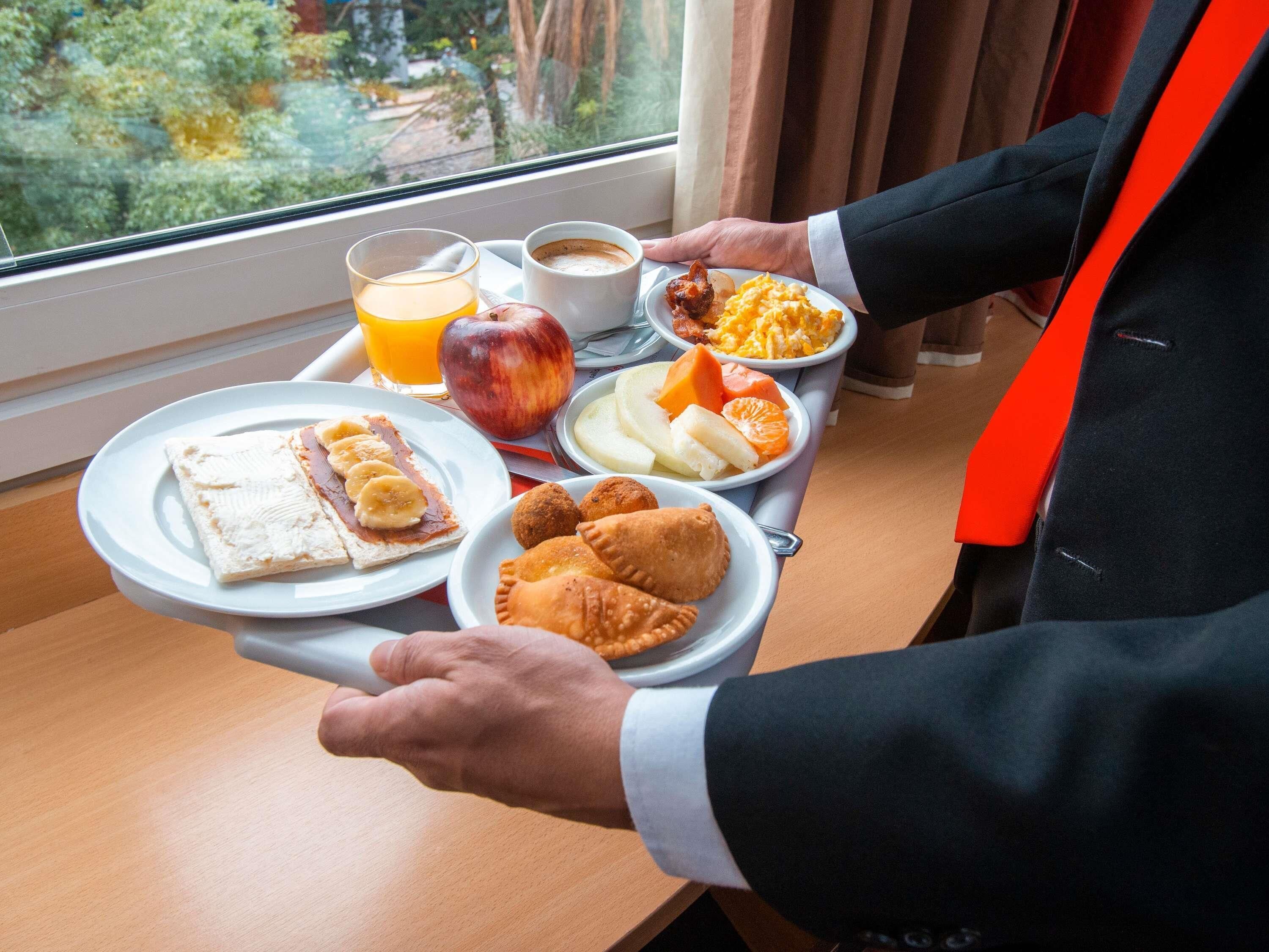 Una bandeja con alimentos para el desayuno, incluyendo tostadas, fruta, pastelería y café.