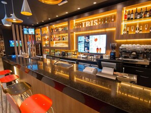 A bar area with a counter, stools, a menu display, and a coffee machine. - Ibis Asuncion (Asunción)