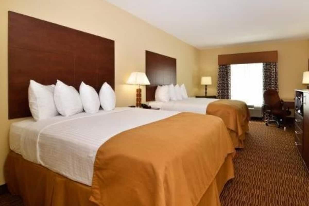 A hotel room with two beds, a desk, and a chair.