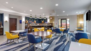 A modern dining area with tables and chairs, a kitchen area, and a television mounted on the wall. - Comfort Suites Natchitoches (Natchitoches)