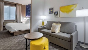A hotel room with a bed, a sofa, a small table, and a lamp. - Comfort Suites Natchitoches (Natchitoches)