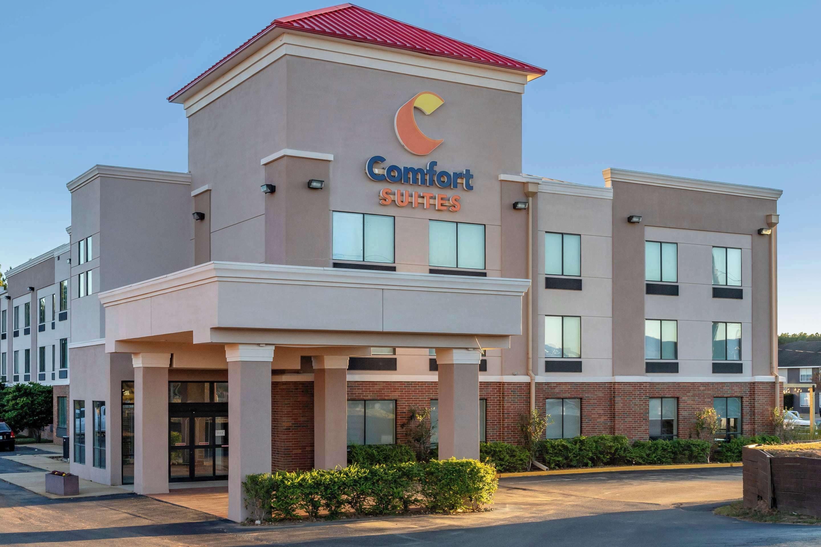 A Comfort Suites hotel with a modern design, featuring a prominent logo and a flat roof.
