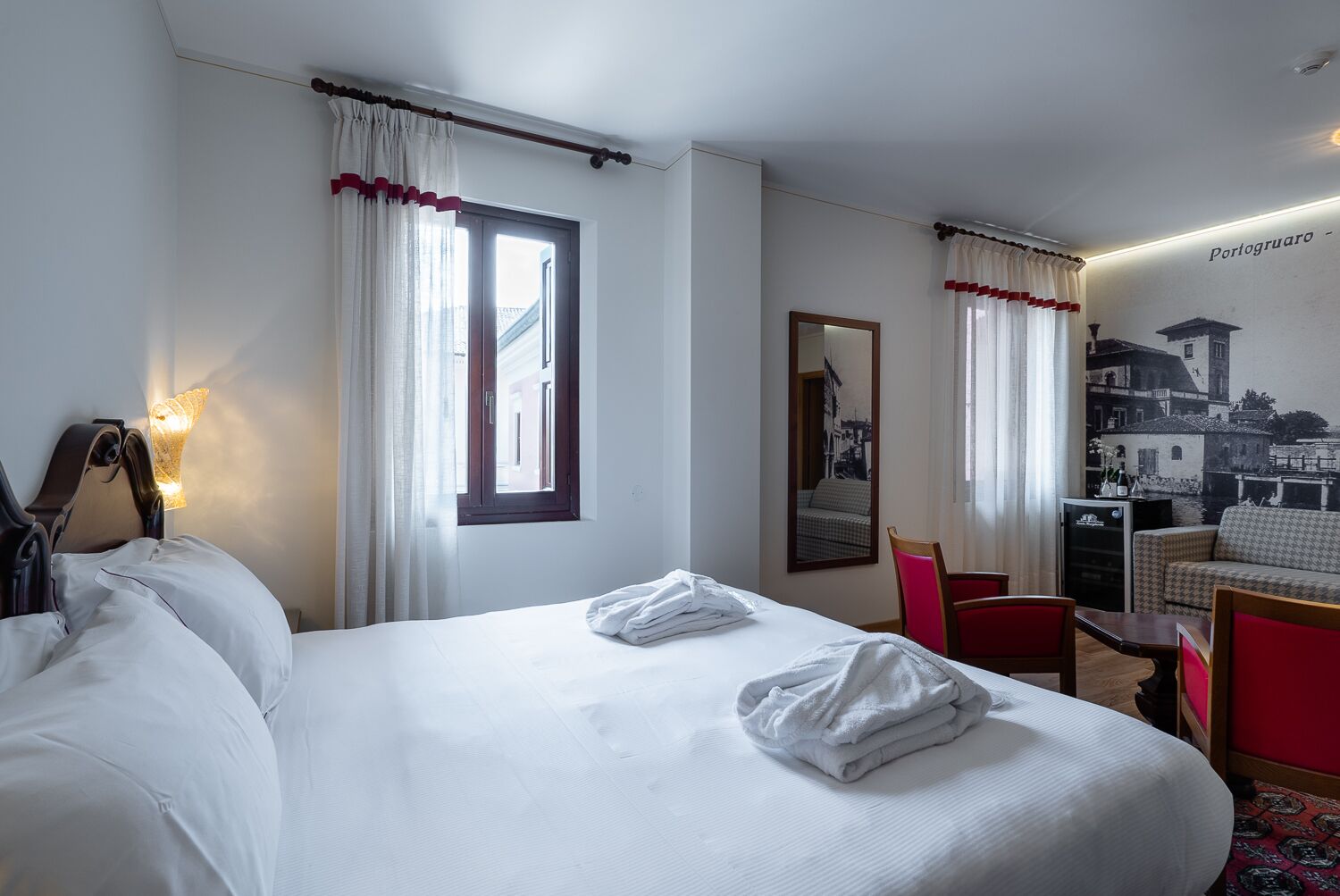 Quarto de hotel com uma cama, uma escrivaninha, uma cadeira e uma pequena mesa.