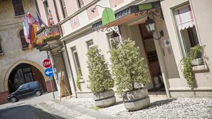 Fachada de hotel con una señal de stop, un letrero verde y dos macetas.